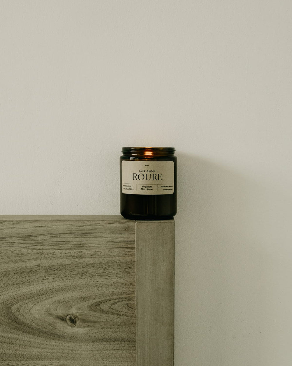 Candle labeled 'Roure' on a wooden surface with a neutral background