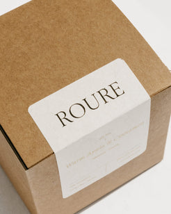 A square kraft paper gift box with a white paper label that reads 'ROURE' in dark serif lettering, photographed on a clean white background.