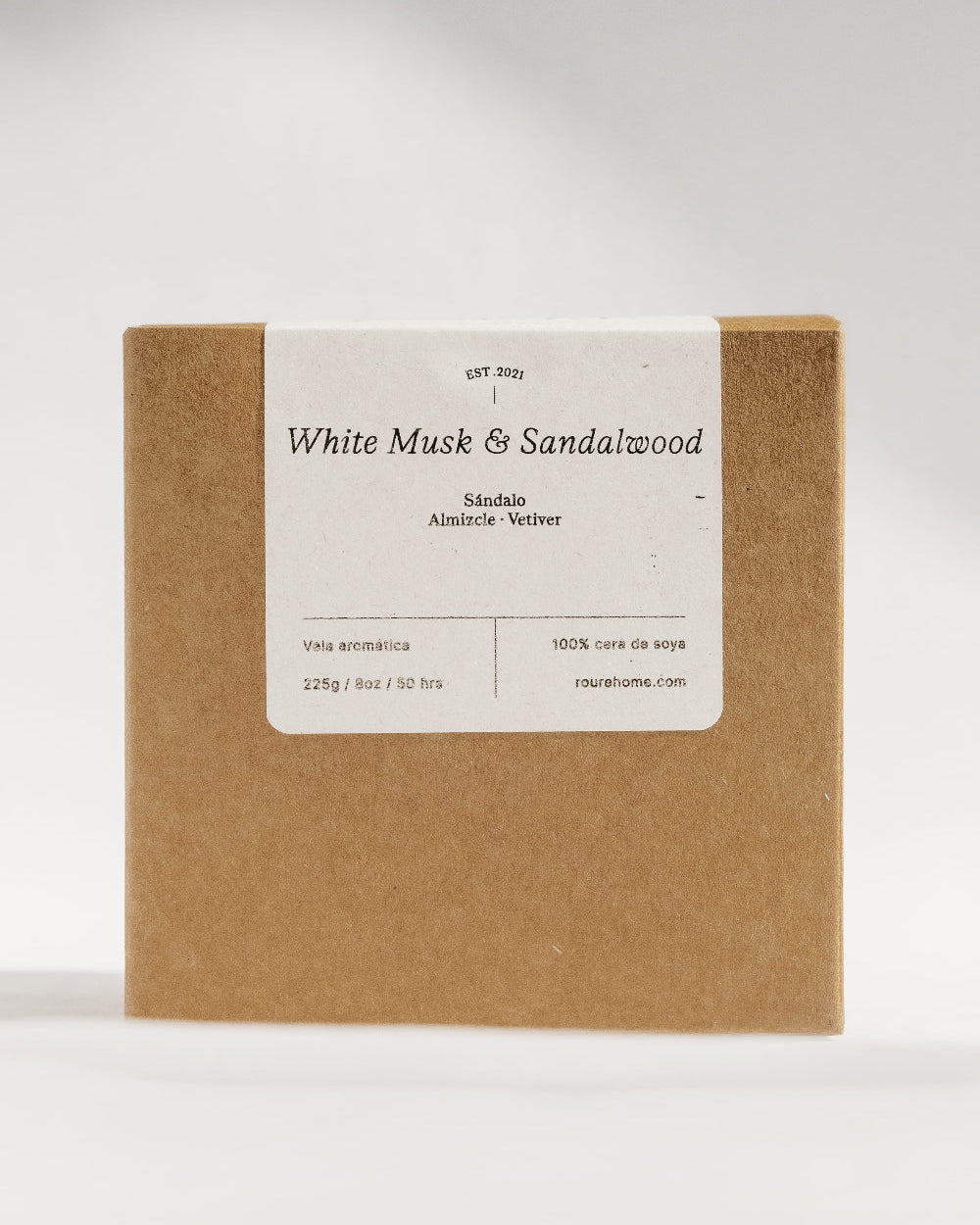 A square kraft paper box with a white label reading 'White Musk & Sandalwood' and smaller scent text, photographed against a clean light gray studio background.