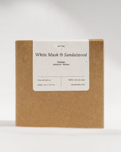 A square kraft paper box with a white label reading 'White Musk & Sandalwood' and smaller scent text, photographed against a clean light gray studio background.